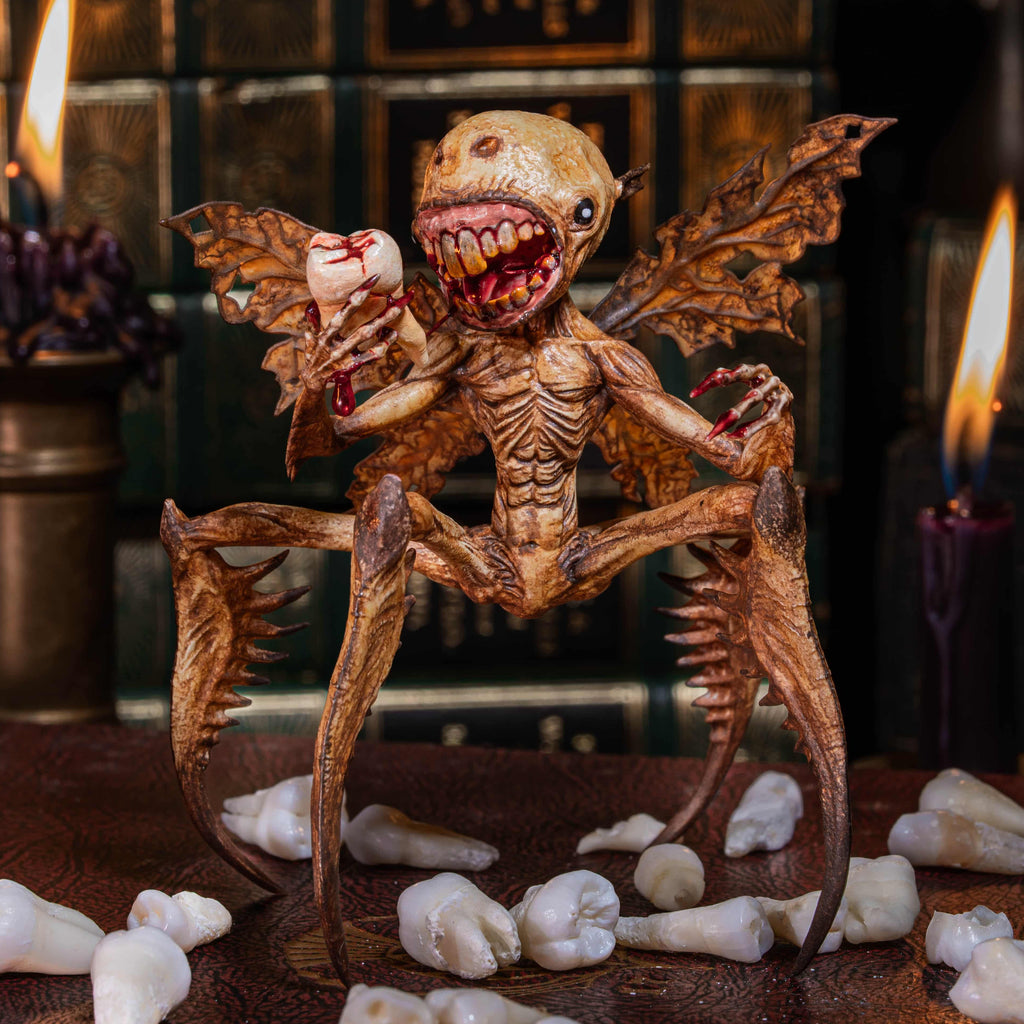 3D printed Tooth Fairy Hellboy figurine with skeletal wings, sharp claws, and a grotesque grin holding a tooth, surrounded by scattered white teeth. Hand-painted in bone, red, and brown tones, this dark fantasy collectible doubles as a tooth holder, making it perfect for gothic decor, horror props, or a unique keepsake for children’s lost teeth.